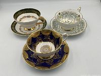 3 English bone china tea cups and saucers displayed together on white surface