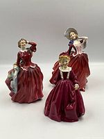 Front view of three Royal Doulton figurines displaying each dressed in flowing red dresses with intricate details and distinct poses.