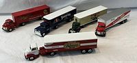 All five beer advertising collectible transport trucks displayed on a white fabric background, showing their scale and paint details.