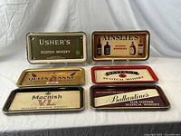 All six vintage Scotch whisky advertising serving trays displayed on white background, showing tray design and condition.