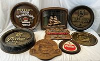 Full view of all 8 vintage pub advertising trays and signs on white background showing condition and branding.