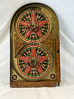 Full view of the antique wooden Lindstrom's Gold Star Toy Pinball Game showing two circular target boards with star designs and point values, and wood frame with wear.
