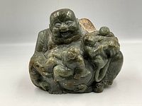 Front view of the carved stone sculpture showing the laughing Buddha and children details.