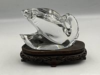 Side angle view of clear Baccarat crystal swan figurine on carved wood stand