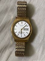 Front view of Bulova Accutron wristwatch showing day and date calendar, CAW TCA Local 707 on dial, gold-tone case, and J.B. Champion watchband.