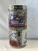 Front view of cylindrical umbrella stand showing panels of figures and florals