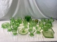 Full set of green uranium Depression glass pieces arranged on white backdrop