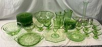 Full lot overview showing assorted green depression uranium glass items arranged on draped white backdrop
