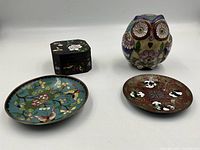 Four hand enameled cloisonne items placed on white background show all four pieces: two small round trays, owl figurine, and lidded box.