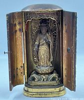 Front view with doors open revealing carved figure on lotus base