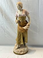 Front three-quarter view of full statue showing figure holding bundles in both hands