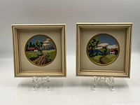 Pair of two framed needlepoint pictures on clear stands, showing complete item view.