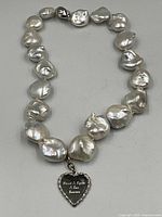 Full necklace laid flat showing pearls, clasp, and pendant