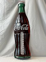 Full view of the large Coca-Cola bottle-shaped wall thermometer showing shape, colors, and general condition.
