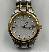 Front view of the watch face showing white dial, luminous hands, date at 3, gold-tone bezel and silver/gold two-tone stainless steel bracelet.