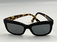 Front angle view of sunglasses showing black cat-eye frame and grey lenses
