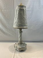 Full view of white porcelain German Blanc de Chine style table lamp with shade on, showing detailed relief work and gold accents.