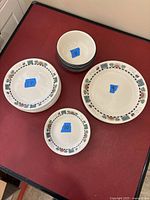 Full set of 9 dinner, 17 lunch, 10 side plates and 8 bowls arranged on a table with blue tape marking quantities