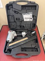Porter Cable clipped head framing nailer in carrying case showing the tool, case compartments, and manual.