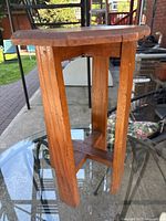 Side view showing the four solid wood legs and cross supports at the base. Shows the height and natural wood finish.