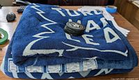 Folded dark blue Toronto Maple Leafs fleece blanket with puck on top showing scale.