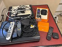 Roku 2 box in original packaging with remote and other cables/remotes on VHS players shown