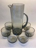 Full view of pitcher surrounded by six roly poly glasses