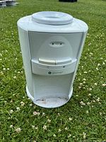 Front view of the Greenway water dispenser showing top loading cap, dispensing buttons, and drip tray area with visible dirt marks.