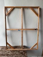 Front view of the rectangular wooden canvas stretcher frame showing cross braces and corner additional braces for support, visible wear marks.