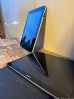 Two tablets, one standing upright and one lying flat on a wooden surface, showing a reflection on the screens.