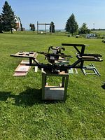 Photo showing Vastex International commercial screen printing press with multiple arms and base stand. Three wooden frame screens with mesh are placed next to the press on the grass.