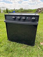 Full front view of the black propane stove and oven combo showing compact size and overall condition with paint splatters.