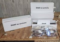 Four Uread Blue Light Blocking glasses boxes displayed with contents: two pairs of glasses each, two carrying cases, and cleaning cloths.