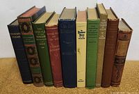Overview of 10 vintage hardcover books in a row, showing spines with titles and authors, varying colors and wear.