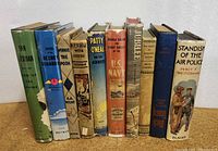 Front view of ten vintage children's books standing upright showing titles and covers.
