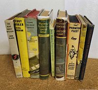 Books standing upright showing spines with titles and authors for identification and condition.