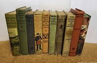 Full view of ten vintage children's books standing upright showing spine titles and varied cover colors.