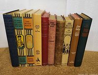 Front view of the ten vintage children's books lined up standing side by side with their spines visible to show titles and bindings.