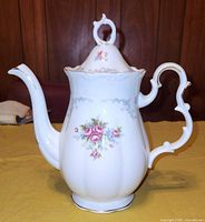 Front view of the tall coffee pot with lid on, showing floral and gold trim details.
