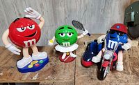 All three M&M's collectible figurines together: red M&M character, green M&M tennis player, blue M&M motorcyclist.