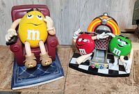 Image showing the yellow M&M character figurine seated in a red armchair and the red and green M&M characters with jukebox collectible side by side.