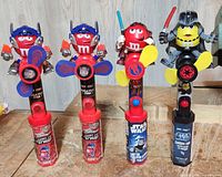 Photo showing 4 M&M's fan collectibles dressed as Transformers and Star Wars characters (Optimus Prime and three Star Wars fans with red and yellow M&M's heads).
