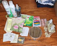 Image of various personal hygiene items including dry shampoo, hair elastics, sachets of creams, clear pump bottles, a round mirror, and other small personal care products.