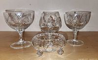Full set showing two dessert glasses, one brandy snifter, and one footed sugar bowl arranged on a wooden surface.
