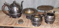Group photo showing vintage silver tea pot, two pedestal plates, cream and sugar set, and flower frog.