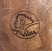 Close-up of the Vilas brand logo stamped on the wood surface of the chest.