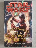 Front cover of Star Wars Luke Skywalker and the Shadows of Mindor paperback book showing Luke with green lightsaber and title text.
