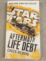 Front cover of the paperback book 'Star Wars Aftermath Life Debt' by Chuck Wendig showing the title, author, and graphic design.