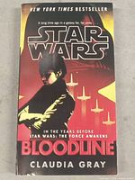 Front cover of 'Star Wars Bloodline' book showing title, author Claudia Gray, and cover art with shadowed figure and spaceships.