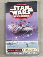 Front cover of Star Wars: The New Jedi Order Dark Tide I Onslaught paperback showing space battle artwork and author name.